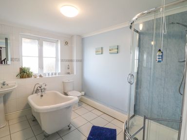 A bathroom with a bathtub toilet sink shower and window at Seascape in Trearddur Bay