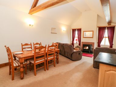 A dining table with six chairs and a living area with brown sofas and a fireplace at The Dairy in Milton near Brampton