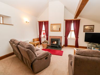 A living room with two brown sofas a fireplace a television and red curtains at The Dairy in Milton near Brampton