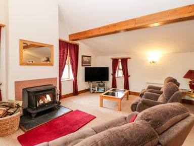 A living room with brown sofas a fireplace a television and wooden beams at The Dairy in Milton near Brampton
