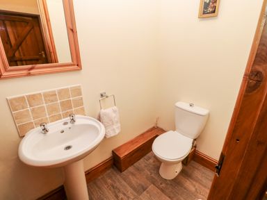 A small bathroom with a white pedestal sink, a toilet, wooden door and mirror at The Dairy in Milton near Brampton