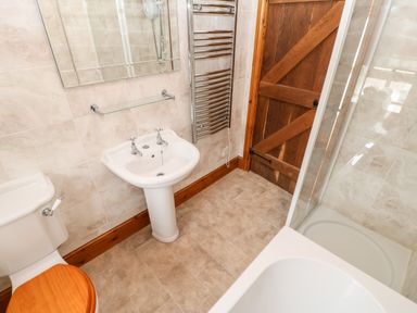 A bathroom with a toilet a sink a shower with glass door a wooden door and a heated towel rail at The Dairy in Milton near Brampton