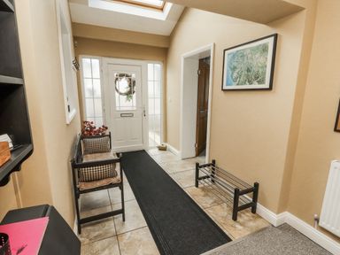 A hallway with a front door and a bench at White Gables in Great Clifton near Cockermouth