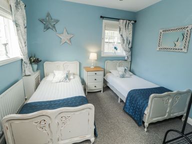 A bedroom with two single beds and a nightstand at White Gables in Great Clifton near Cockermouth
