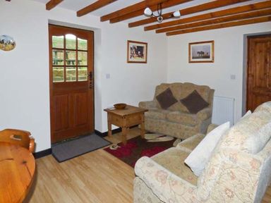 A living room with two sofas a wooden door a wooden coffee table and framed pictures on the walls at The Stable in Aislaby near Whitby