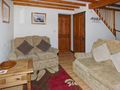A sitting room with two sofas a wooden table a rug and wooden doors at The Stable in Aislaby near Whitby