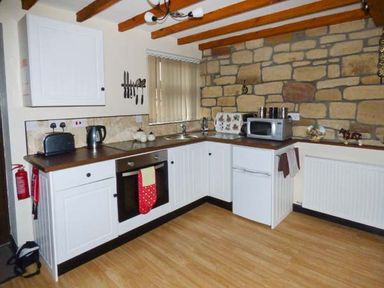 A kitchen with white cabinets wooden countertop microwave oven toaster and kettle at The Stable in Aislaby near Whitby