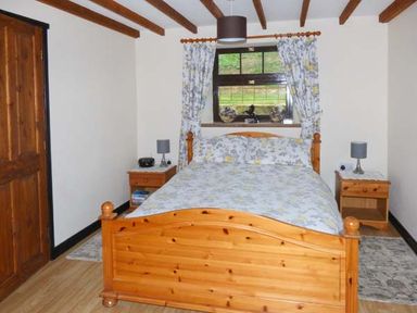 A bedroom with a wooden bed and bedside tables under a window at The Stable in Aislaby near Whitby