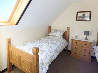 A bedroom with two single wooden beds a wooden chest of drawers with a lamp and a framed picture on the wall at The Stable in Aislaby near Whitby