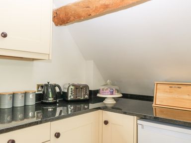 A kitchen countertop with a kettle, toaster, storage jars, cake stand with cover, and a bread box at Shepherd's Barn Between Milborne St Andrew and Winterborne Whitechurch