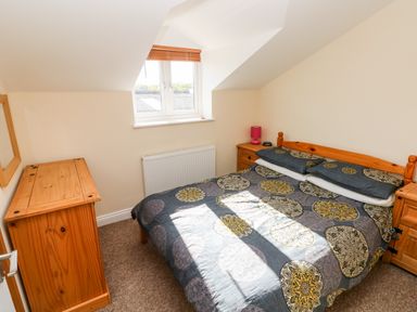 A bedroom with a double bed bedside tables a wooden chest of drawers and a window at Saddlers Cottage Berllandeg Farm in Clunderwen near Narberth