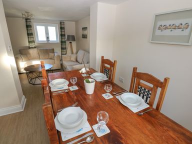 A dining table set with plates and glasses with sofas and a coffee table in the background at Saddlers Cottage Berllandeg Farm Clunderwen near Narberth