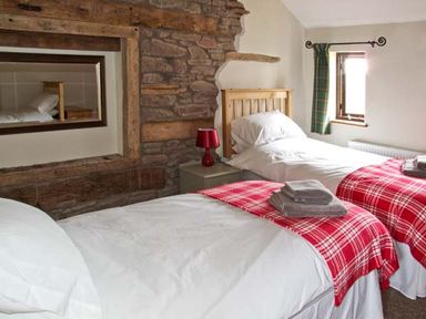 A bedroom with two single beds with white bedding and red plaid blankets at Bushmills Kerry's Gate near Abbey Dore
