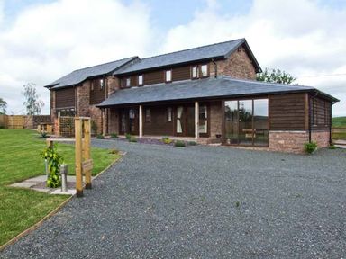 A two-story house with stone and wooden exterior and a gravel driveway at Bushmills in Kerrys Gate near Abbey Dore