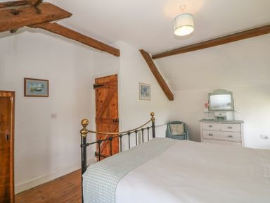 A bedroom with a metal bed frame wooden door dresser and a chair at Ty Fferm Bodlasan Llanfachraeth near Valley