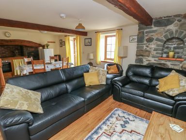 A living room with sofas and a dining area at Daffodil Cottage in Caeathro near Caernarfon