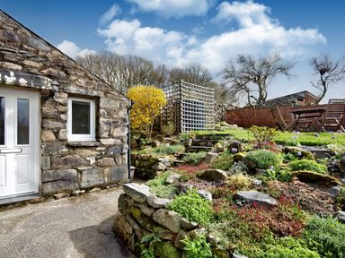 A stone wall house with a garden and outdoor wooden table and chairs at Ty Capel Jeriwsalem in Bronaber near Trawsfynydd