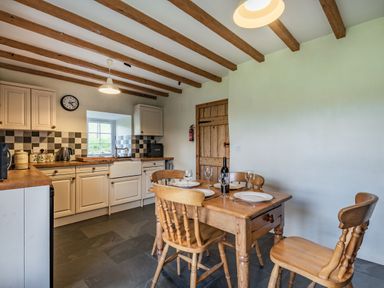 A kitchen with wooden dining table and chairs and checkered backsplash at Ty Capel Jeriwsalem in Bronaber near Trawsfynydd