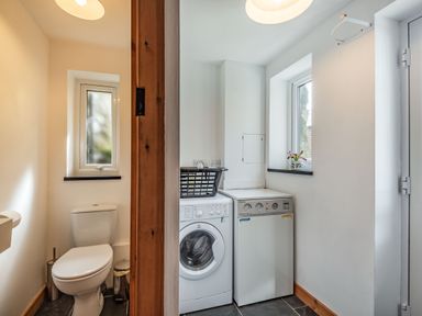 A toilet and a laundry area with washing machine and dryer at Ty Capel Jeriwsalem in Bronaber near Trawsfynydd