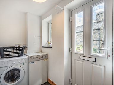 A utility room with a washing machine and boiler next to a door with windows at Ty Capel Jeriwsalem Bronaber near Trawsfynydd