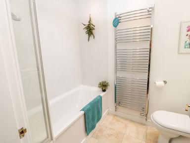 A bathroom with a bathtub towel plant toilet and heated towel rail at Beudy Hywel in Llanrug near Llanberis