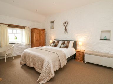 A bedroom with a double bed wooden wardrobe bedside table and a chair at Bwthyn Bach in Newport