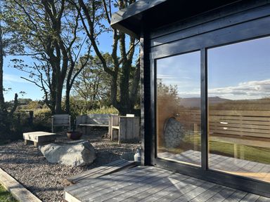 An outdoor area with wooden seating and a table at Bwthyn Bach in Newport