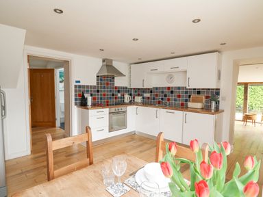 A kitchen with white cabinets and colorful tiled backsplash at Y Cwtch in Newport