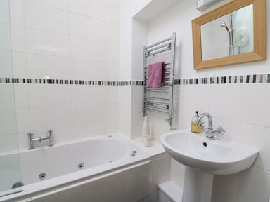 A bathroom with a bathtub a sink a mirror and a towel on a heated rail at Y Cwtch in Newport