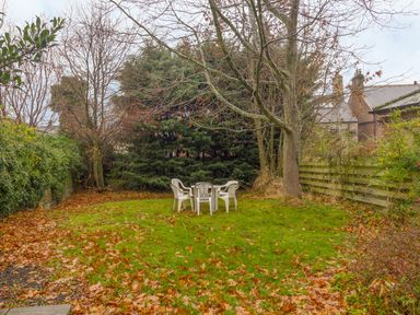 A garden with a table and four chairs surrounded by trees at The Old Exchange in Corbridge near Hexham