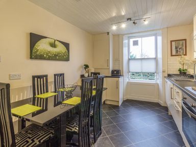 A kitchen with a black dining table and six chairs a window countertop appliances and cabinets at The Old Exchange in Corbridge near Hexham