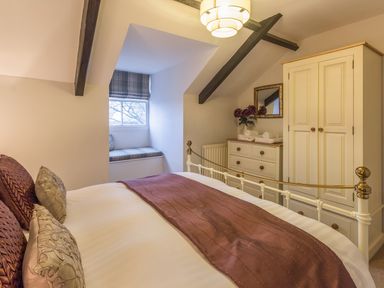 A bedroom with a bed a window seat a chest of drawers a wardrobe and exposed beams at The Old Exchange in Corbridge near Hexham
