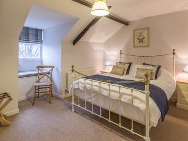 A bedroom with a double bed bedside tables lamps a wooden chair and a window seat at The Old Exchange in Corbridge near Hexham