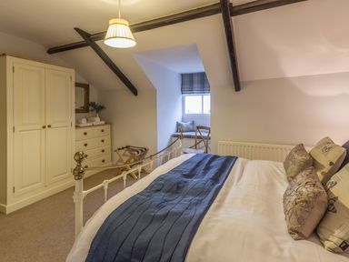 A bedroom with a bed a wardrobe chest of drawers and a window seat at The Old Exchange in Corbridge near Hexham
