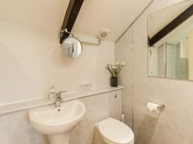 A bathroom with a sink toilet wall mirror and flowers on a shelf at The Old Exchange in Corbridge near Hexham