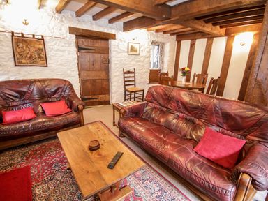 A living room with two leather sofas a wooden coffee table and dining table at Nant Cottage in Llanrwst near Betws-y-Coed