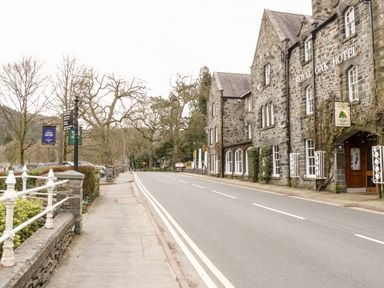 A street view with a stone building named Royal Oak Hotel on the right and a sidewalk with signposts on the left at Nant Cottage in Llanrwst near Betws-y-Coed