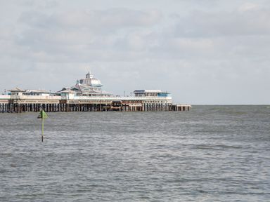A large pier extending into the sea with a domed building on it under a cloudy sky