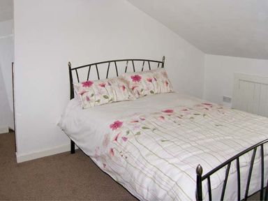 A bedroom with a bed featuring floral bedding and pillows at Hendre Aled Cottage 3 in Llansannan