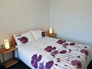 A bedroom with a double bed with floral bedding and two bedside tables with lamps at Hendre Aled Cottage 1 Llansannan near Llanrwst