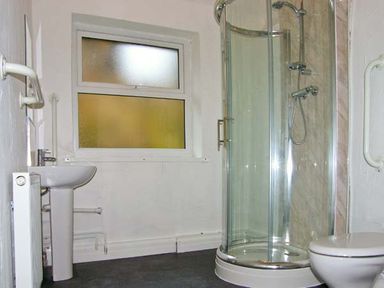 A bathroom with a corner glass shower, a pedestal sink, a toilet, and a frosted window at Hendre Aled Cottage 1 in Llansannan near Llanrwst
