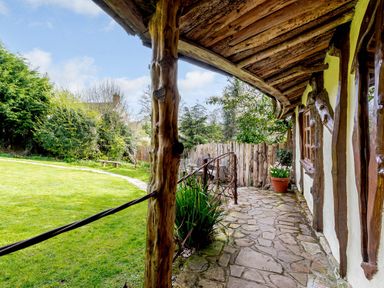 A stone path alongside a rustic timber house with wooden beams and a covered porch at Brookbank Folly in Mitcheldean