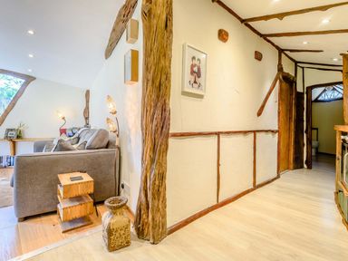 A living room with a gray sofa wooden side tables floor lamps and wooden beams on the walls at Brookbank Folly in Mitcheldean