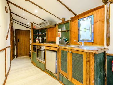 A kitchen with wooden cabinets oven sink and stained glass window at Brookbank Folly in Mitcheldean