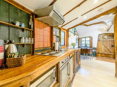 A kitchen with wooden countertops appliances and a dining table near a window at Brookbank Folly in Mitcheldean