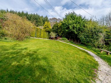 A garden with a gravel path lawn trees and bushes at Brookbank Folly in Mitcheldean