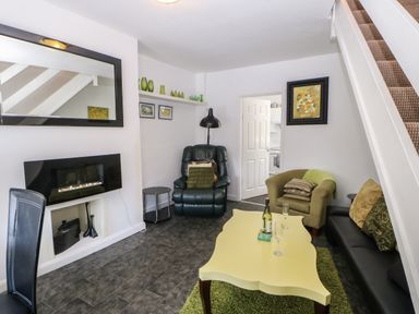 A living room with a yellow coffee table and green chair at Hollie Cottage in Haltwhistle