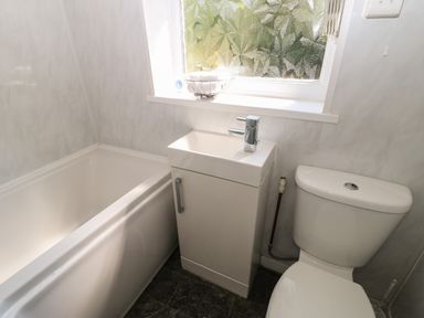 A bathroom with a bathtub sink and toilet under a frosted window at Hollie Cottage in Haltwhistle