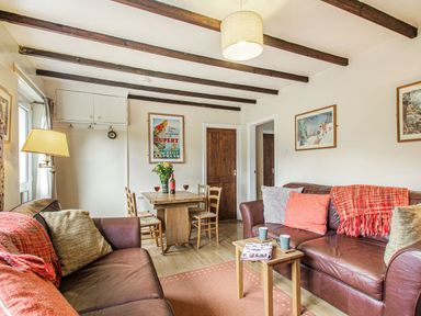 A living room with two brown sofas a wooden table with chairs and framed pictures on the walls at Penlan in Beddgelert