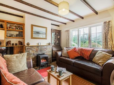 A living room with two brown leather sofas a small wooden table with mugs a framed painting and a window at Penlan in Beddgelert